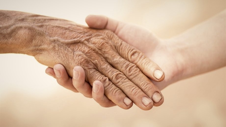 Eine ältere Hand liegt in einer jüngeren Hand